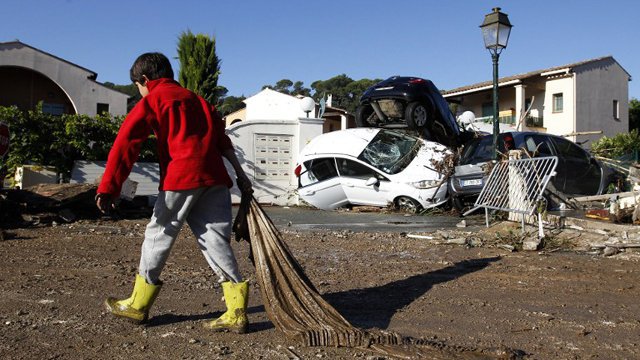 Photo d’un enfant participant au nettoyage des débris autour de son lotissement après une inondation survenue dans les Alpes-Maritimes en octobre 2015.